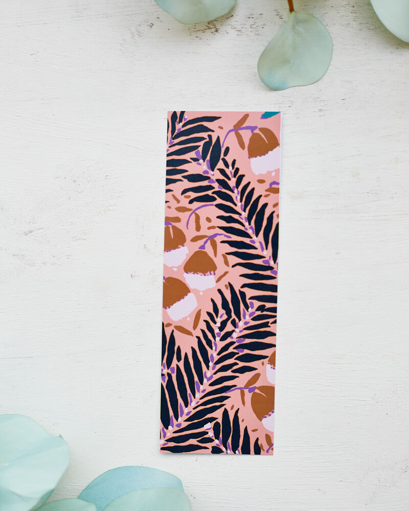 A glossy 2 x 6 bookmark depicting scrolling branches, abstract flowers, and a peachy pink background.