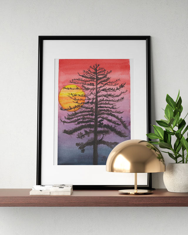A shelf with a small lamp, a small plant and a watercolor painting of a thin black tree in front of a sunset with a red sky fading into black.