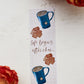 A glossy 2 X 6 bookmark with a pale yellow grid background depicting large mugs of tea and biscuits with the words "life begins after chai..." in script lettering across the middle.