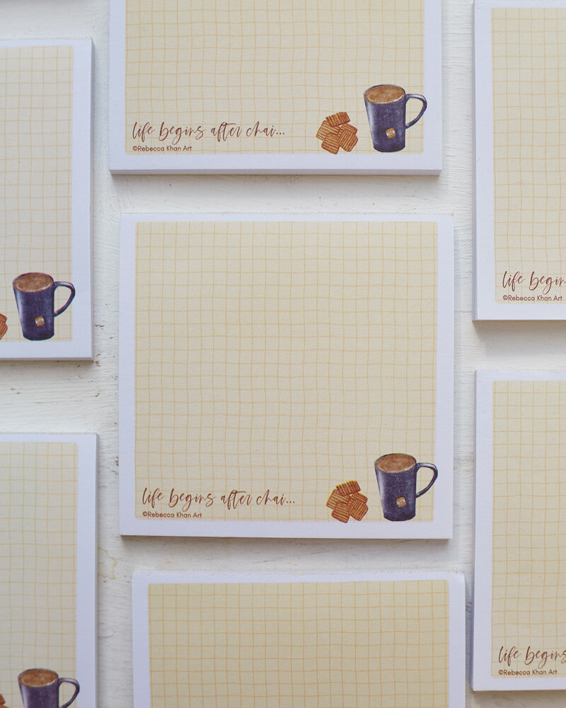Multiple notepads with a pale yellow grid background with a white border, on the bottom a cup of tea and biscuits are depicted with the words "life begins after chai..." in script lettering.