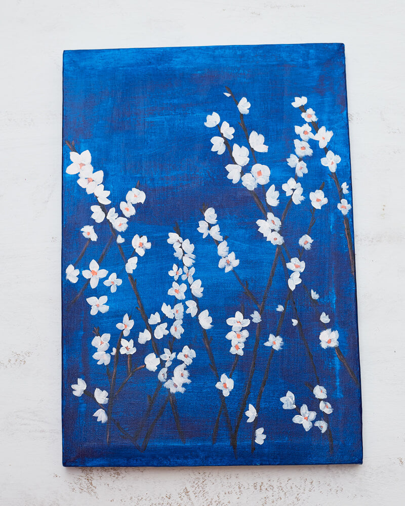An acrylic painting on canvas depicting white blossoms against a moody blue background.