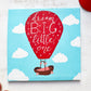 Acrylic painting on canvas of a bright red hot air balloon featuring the words "Dream Big Little One" in hand lettering ascending the sky with a baby basket.  The painting is surrounded by a bright red child's cap and red shoes.