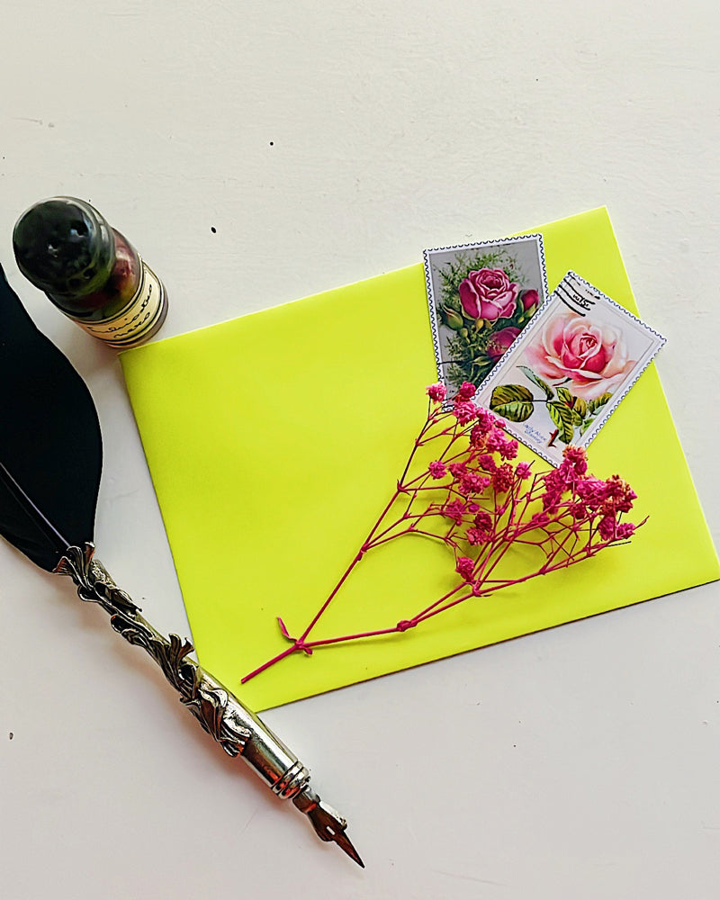Two vintage stamp stickers on an envelope with some dried flowers, a quill and an ink bottle.